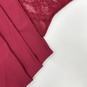 Close-up detail of burgundy women's slip dress featuring delicate lace patchwork and smooth fabric.