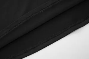 Black dress detail view showing fine double-needle stitching craft and premium fabric texture.