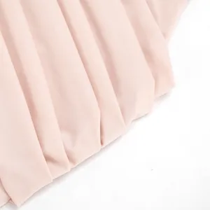 Pink pleated dress detail close up showing soft fabric texture and fine pleated design.