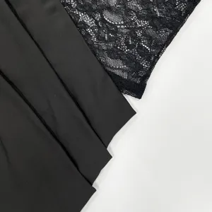 Black lace fabric detail of women's dress, showing smooth pleated material and mesh.