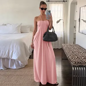 Zomerse roze maxi-jurk met halternek en open rug, perfect voor een elegante vakantielook.