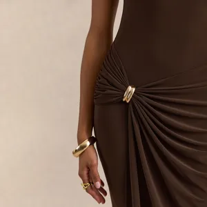 Détail d'une élégante robe marron avec drapé de taille asymétrique et boucle de anneau doré chic.