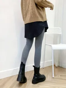 Details of layered outfit with cable-knit sweater, false hem skirt, grey leggings and boots.