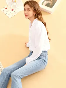 Detailaufnahme einer weißen Damenbluse mit Rüschenkragen und blauer Jeans, schicker Stil.
