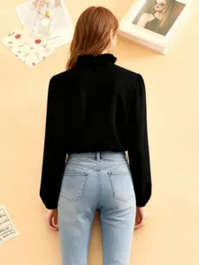 Elegante schwarze Damen Langarm Bluse mit Rüschenkragen und hellblauen Jeans kombiniert.
