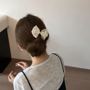 Close-up detail of a delicate white mesh bow hair clip worn elegantly on braided hair bun.