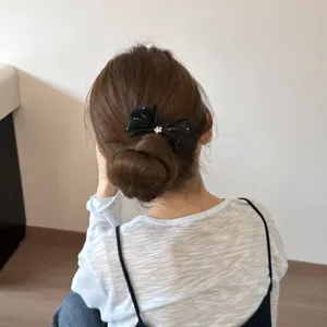 Detail shot showing a black mesh bow hair clip worn elegantly on a messy bun, sweet style.
