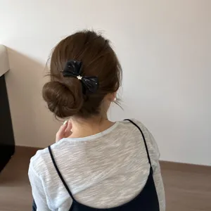 Detail shot of a sweet black ribbon hair bow clip, elegant hair accessory for styling.
