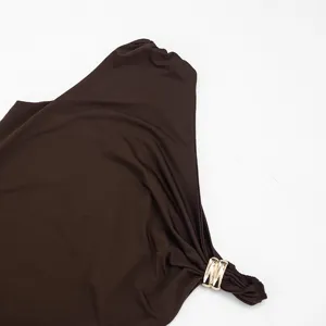 Gros plan détail de la robe asymétrique marron foncé avec boucle en anneau métallique.