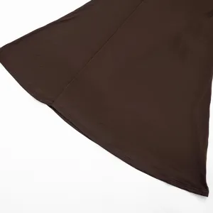 Détail de l'ourlet de la robe marron avec texture de tissu lisse et couture propre, fond blanc.