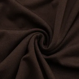 Gros plan détaillé de la texture du tissu côtelé marron foncé, montrant un tricot fin et un drapé.