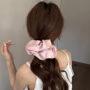 Close-up detail of soft pink satin hair scrunchie, fluffy volume accessory showcasing smooth fabric.