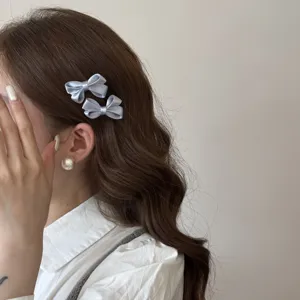 Light blue satin bow hair clip detail, close up view of cute Korean style accessory for girls.