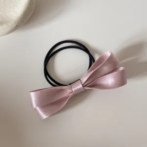 Detalle coletero lazo satén rosa, goma de pelo minimalista elegante para coleta diaria.