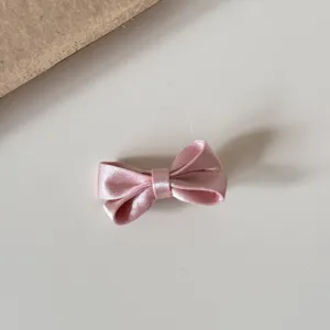 Pink satin bow hair clip detail shot, cute Korean style hair accessory for girls and kids.