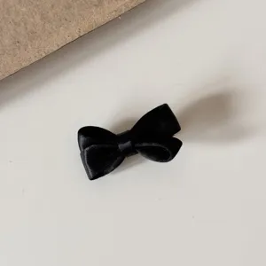 Detailed close-up of a cute black satin bow hair clip, elegant and minimalist design.