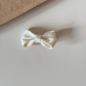 Chic white satin bow hair clip for girls, delicate mini hair accessory for cute daily styling.