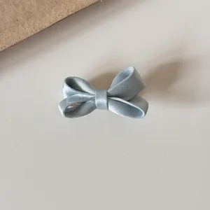 Light blue satin bow hair clip detail shot, cute hair accessory for kids and girls.