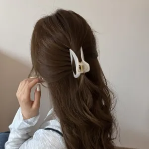 Detail shot of a stylish white hollow curved hair claw clip worn on brown hair, elegant accessory.