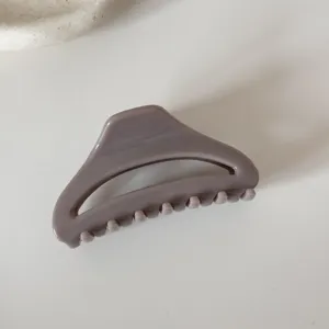 Close-up detail of a taupe curved hollow hair claw clip, minimalist style accessory.