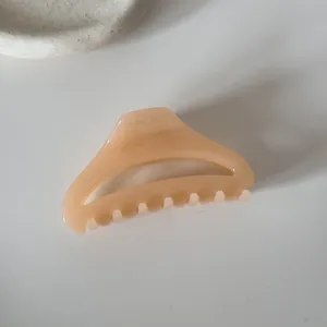 Detailed view of a minimalist peach nude acrylic hair claw clip with a hollow curved design.