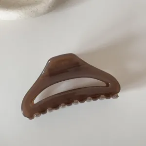Brown hollow hair claw clip for women, elegant minimalist shark clip for styling thick hair.