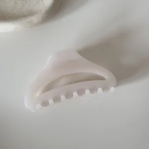 Medium hollow curved hair claw clip detail shot, minimalist milky pink design for styling.