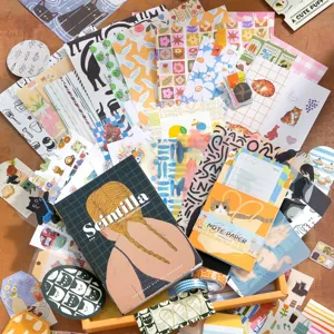 Set de caja de regalo de papel para scrapbooking con varios cuadernos y pegatinas decorativas.