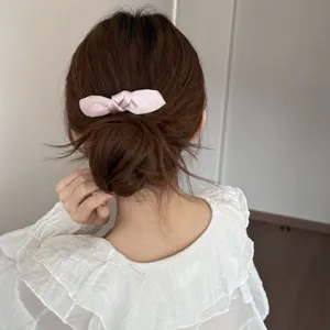 Pink satin bow hair clip detail view, showing elegant back hair styling and cute pink bow accessory.