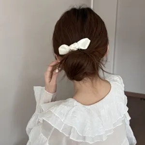 Detailed shot of white satin ribbon hair comb accessory, elegant low bun styling, daily wear.