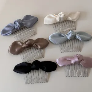 Detailed view of multiple colored bow hair combs, fabric satin design with metal teeth.