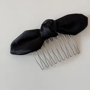 Detailed shot of black satin ribbon hair comb with silver metal teeth for elegant hairstyles.