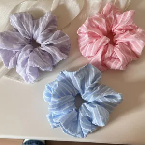Detail van gestreepte stoffen haarelastiekjes in paars, roze en blauw voor styling.