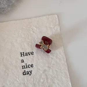 Gros plan détaillé d'une mini pince à cheveux rouge foncé avec décor en strass.
