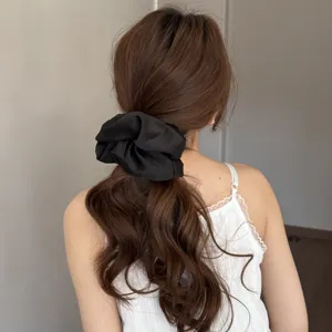 Detailed view of the elegant black satin hair scrunchie showing soft fabric and texture.