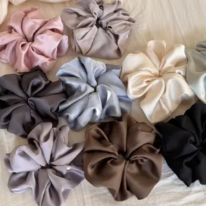 Close-up detail of multi-color satin scrunchies, soft fabric hair ties set in various elegant shades.