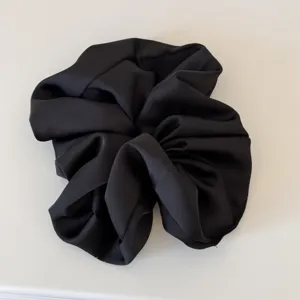 Black satin hair scrunchie detail view, elegant voluminous hair tie accessory for women.