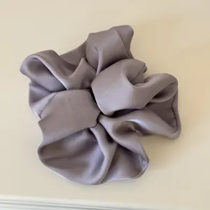Close-up detail of a soft satin hair scrunchie in pastel purple, highlighting smooth glossy finish.