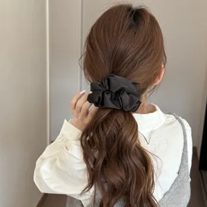 Black satin hair scrunchie detail view, elegant hair tie accessory for women daily styling.