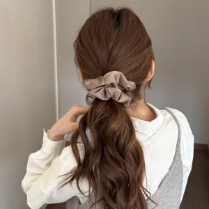 Close-up detail of the elegant satin hair scrunchie worn on a ponytail, smooth texture.