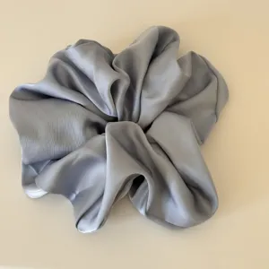 Close-up detail of large grey satin hair scrunchie, smooth glossy fabric for daily hair styling.