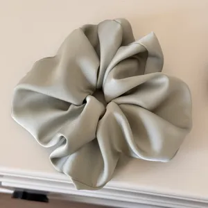 Detailed close-up of the smooth satin hair scrunchie texture, displaying elegant shine.