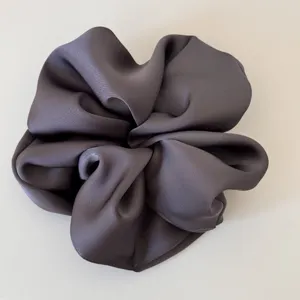 Dark grey satin scrunchie detail close-up, smooth fabric texture and glossy hair accessory.