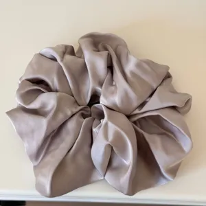 Close-up detail shot of a plush satin hair scrunchie, soft texture and elegant sheen.