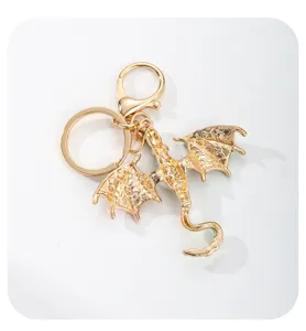 Detailed view of gold metal dragon keychain with colorful wings and secure lobster clasp.