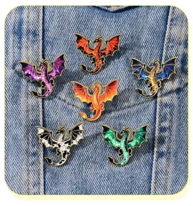 Detailed close-up view of colorful fantasy dragon enamel pins displayed on denim fabric.