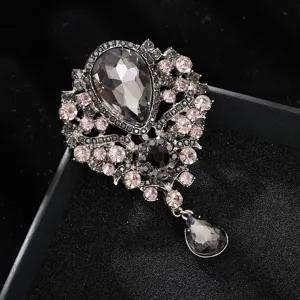 Nahaufnahme einer Vintage Kristall Strass Anhänger Brosche in Silber mit grauen und rosa Steinen.