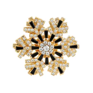 Broche de copo de nieve dorada con pedrería blanca brillante y finos cristales negros.