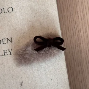 Detailansicht braune Plüsch Haarklammer mit dunkler Samtschleife, weiches Winter Haaraccessoire.