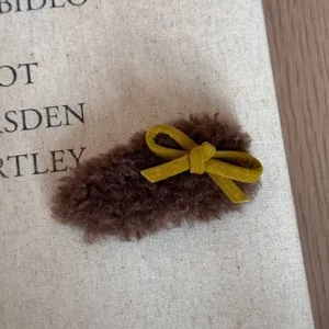 Detaillierte Ansicht der braunen Plüsch-Haarspange mit weicher Textur und gelber Schleife.